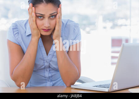 Anxieux businesswoman having sa tête dans les mains dans son bureau Banque D'Images
