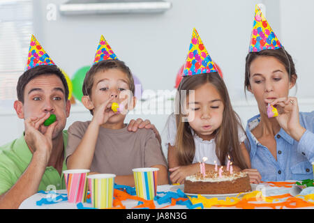 Famille avec party horn celebrating their daughter party qui souffle ses bougies Banque D'Images