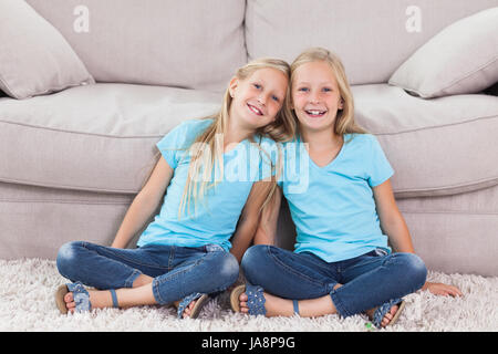 Des jumeaux assis sur un tapis dans le salon Banque D'Images