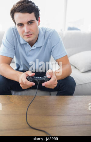 Homme concentré à jouer à des jeux vidéo pendant qu'il est assis sur un canapé Banque D'Images