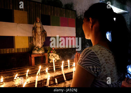 Une femme priant au vieux couvent de l'Église catholique romaine La Purisima Concepcion de la Virgen Maria Église Paroissiale communément appelée Eglise de Baclayon dans la municipalité de Baclayon, dans l'île de Bohol situé dans la région de Visayas central des Philippines Banque D'Images