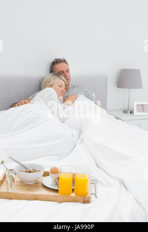 Couple avec plateau de petit-déjeuner à bout de lit à la maison dans la chambre Banque D'Images