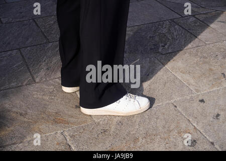 Homme debout sur le trottoir, détail des jambes et les pieds. Il porte une paire de baskets blanc Banque D'Images