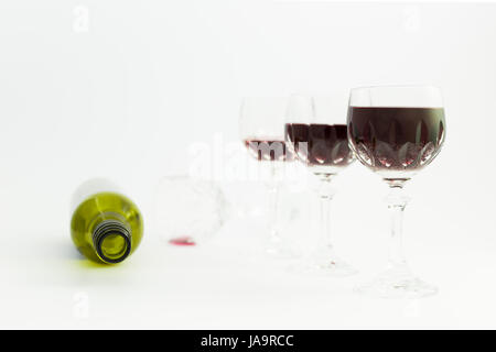 Concept de la consommation d'alcool, l'alcoolisme et l'abus par une ligne de beaux verres de cristal rempli de vin rouge et une bouteille vide. Étapes de drin Banque D'Images
