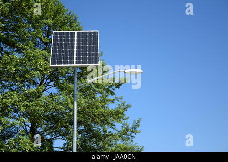 Lampadaire moderne avec panneau solaire sur fond de vert des arbres et ciel bleu Banque D'Images