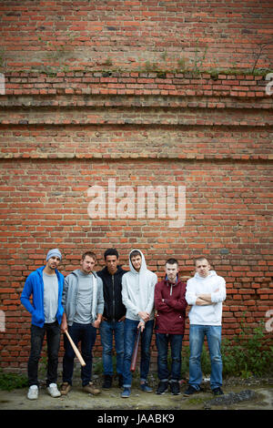 Portrait de plusieurs street hooligans ou rappeurs tiennent contre brick wall Banque D'Images