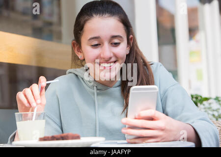 Jeune fille au Café Lecture Text Message On Mobile Phone Banque D'Images