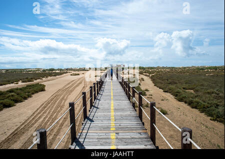 Couple en train de marcher le long de boarwalk sur Praia de Cabanas, Portugal Banque D'Images