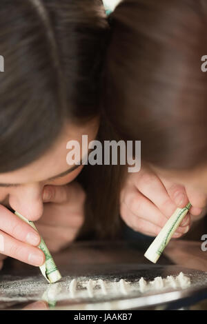 Deux filles de renifler une substance blanche illégale avec rolled up notes off un miroir Banque D'Images