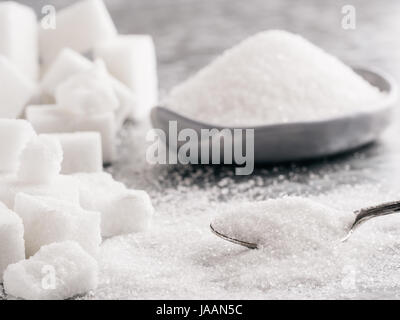 Arrière-plan de sucre. Le sucre en cubes, le sucre granulé dans spoon et la plaque. Sucre blanc sur fond gris fer galvanisé. Copier l'espace. Banque D'Images