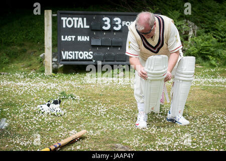 Un batteur revient à l'pavilion et supprime ses coussinets pendant un match amical entre Cravens Cavaliers et Lynton & Lynmouth Cricket Club à leur base au sol à l'intérieur de la Vallée des Roches, North Devon. Banque D'Images