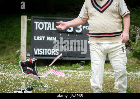 Un batteur retourne au pavillon et retire ses coussins lors d'un match annuel entre les Cavens Cavaliers et le Lynton & Lynmouth cricket Club à leur sol, dans la vallée des Rocks, dans le nord du Devon. Banque D'Images