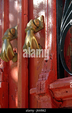 Une vieille porte rouge avec deux golden hand-comme les heurtoirs sur elle. Banque D'Images