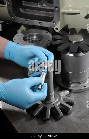 Un ingénieur utilise un micromètre pour mesurer le diamètre des composants au cours de l'assemblée d'un compresseur industriel Banque D'Images