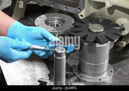 Un ingénieur utilise un micromètre pour mesurer le diamètre des composants au cours de l'assemblée d'un compresseur industriel Banque D'Images