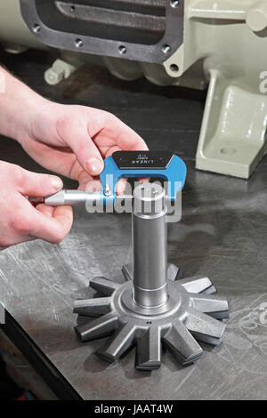 Un ingénieur utilise un micromètre pour mesurer le diamètre des composants au cours de l'assemblée d'un compresseur industriel Banque D'Images