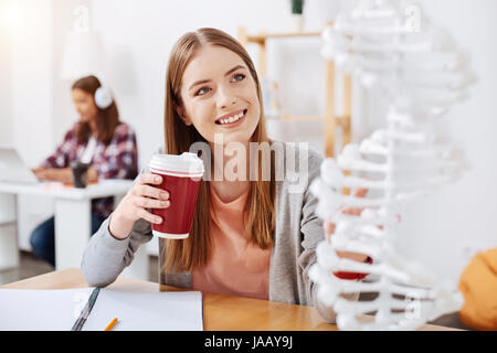 Me demande de progrès. Jolie jeune femme enthousiaste assis dans la classe et l'étude de la génétique qui suit des cours à l'université Banque D'Images