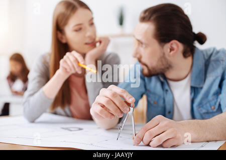 Vous permet d'ajouter un détail. Jeune ingénieur d'imagination productive donnant son collègue et conseils tout en l'aidant à travailler sur le nouveau projet de dessin de la BUI Banque D'Images