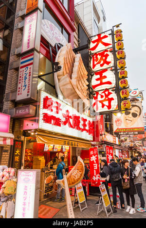 Domaine de Dotonbori Osaka. Comptoir à emporter à 'Osaka' Ohsho, servant des Gyoza. Les gens faire la queue. Un témoin lumineux et l'affichage grand format. La nuit. Banque D'Images