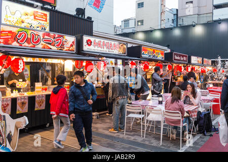 Osaka, Dotonbori. Occupé à l'extérieur zone de restauration avec rangée de divers stands de restauration rapide et d'un coin salon pour les clients. En début de soirée. Banque D'Images