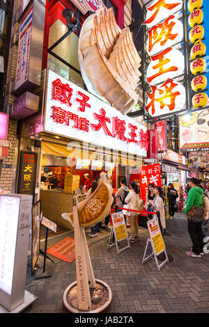 Domaine de Dotonbori Osaka. Comptoir à emporter à 'Osaka' Ohsho, servant des Gyoza. Les gens faire la queue. Un témoin lumineux et l'affichage grand format. La nuit. Banque D'Images