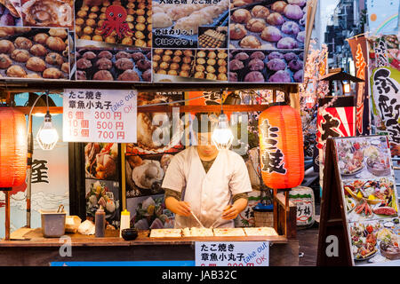 Dotonbori, un quartier de divertissement d'Osaka. Comptoir à emporter Takoyaki avec l'homme de préparer des aliments. La nuit. Inscrivez-vous en anglais, "Sortir OK'. Chochin Banque D'Images