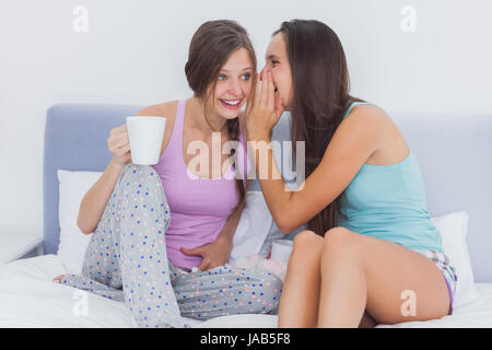 Friends sitting in bed commérage à la maison dans la chambre Banque D'Images