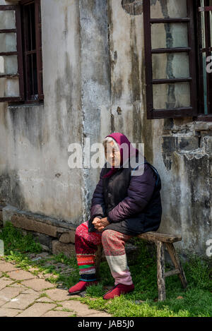 Femme âgée assise devant sa maison, l'ancienne ville d'eau de Tongli, Suzhou, Province de Jiangsu, Chine Banque D'Images