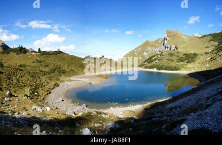 Tannheimer Berge Die in Tirol, Oesterreich ; Blick auf einen kleinen Bergsee mit Wasser und Spiegelung türkisfarbenen ; mit terrasse Tag im Herbst mit blauen Himmel und Wolken weißer bär, le panorama des montagnes de Tannheim au Tyrol, Autriche ; vue sur un petit lac de montagne aux eaux turquoises et de réflexion ; journée d'automne ensoleillée avec ciel bleu et nuages blancs ; panorama Banque D'Images