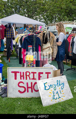 Une jeune femme en regardant à travers les racks dans un magasin d'aubaines au cours de l'openair Meadows Festival à Édimbourg. Banque D'Images