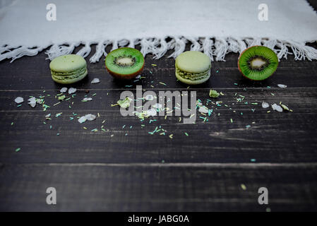 Macarons et kiwi vert comme une frontière sur une nappe blanche avec fond en bois Banque D'Images