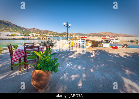 Chaises avec tables de taverne grecque typique au port de makri gialos, Crète, Grèce. Banque D'Images