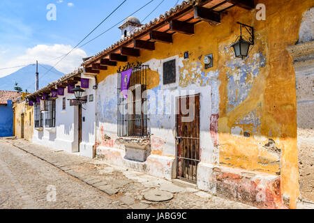 Antigua, Guatemala - 13 avril 2017 : les maisons coloniales avec des bannières en Carême violet & windows volcan agua derrière en site du patrimoine mondial de l'UNESCO Banque D'Images
