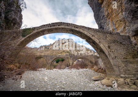 - Noutsou kokkori vieux pont en pierre voûtée sur le canyon de vikos, zagorochoria, Grèce. hiver coucher du soleil avec de la glace et des glaciers sur la rivière. Banque D'Images