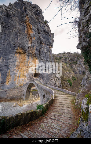 - Noutsou kokkori vieux pont en pierre voûtée sur le canyon de vikos, zagorochoria, Grèce. hiver coucher du soleil avec de la glace et des glaciers sur la rivière. Banque D'Images