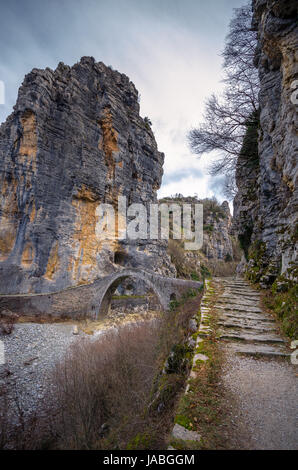 - Noutsou kokkori vieux pont en pierre voûtée sur le canyon de vikos, zagorochoria, Grèce. hiver coucher du soleil avec de la glace et des glaciers sur la rivière. Banque D'Images