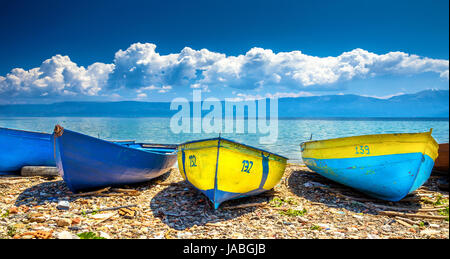 Bateaux colorés sur la plage au lac d'Ohrid avec ciel nuageux, Albanie. Banque D'Images