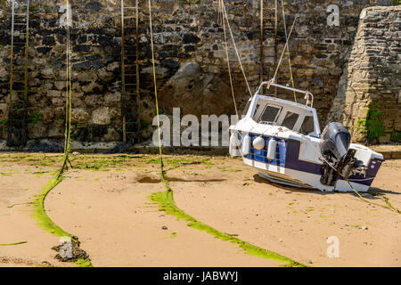 Moteur unique bluw et blanc bateau amarré dans le port à marée basse. Tenby. Pembrokeshire. UK Banque D'Images