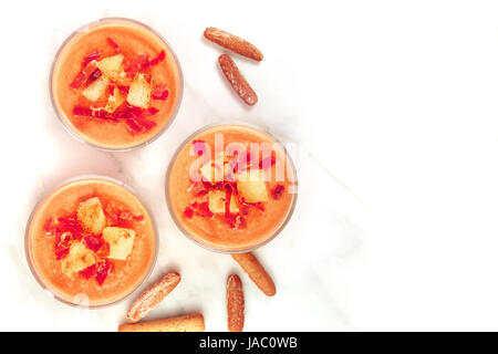 Une photo d'un salmorejo, soupe froide espagnole traditionnelle, servie dans des verres avec des bâtonnets de pain, garnie de jambon et croûtons, tourné par le haut avec un Banque D'Images