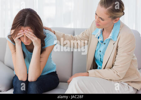 Worried woman être réconforté par son thérapeute et assis sur le canapé Banque D'Images