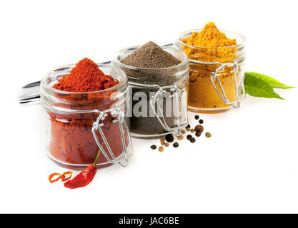 Trois contenants en verre rempli d'épices culinaires au sol avec des piments, poivre noir et la poudre de curry sur un fond blanc Banque D'Images