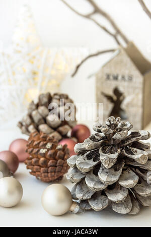 Blanc décoration de Noël composition, big pommes de pin, boules éparses, brillante étoile, bougeoir en bois, sec les branches d'arbres en arrière-plan, minimali Banque D'Images