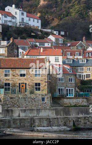 Vue panoramique de joli village côtier pittoresque & seaside maisons serrées sur la falaise, au-dessus du mur du port - Runswick Bay, Yorkshire, Angleterre, Royaume-Uni. Banque D'Images