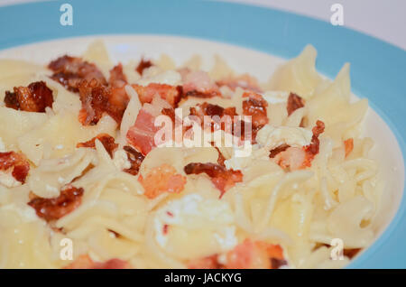 Des pâtes avec du fromage cottage et de bacon sur une plaque bleue Banque D'Images