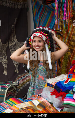 Une belle jeune femme portant Native American hat plume. avec des tissus de couleurs background Banque D'Images