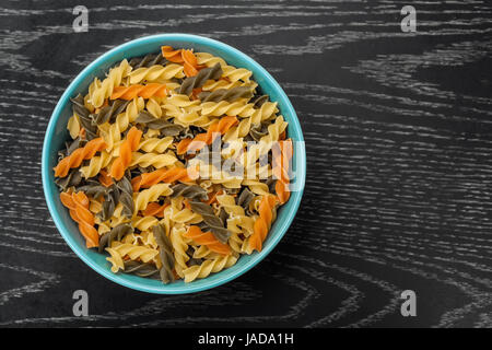 Fusilli colorés en bleu bol sur la table en bois Banque D'Images