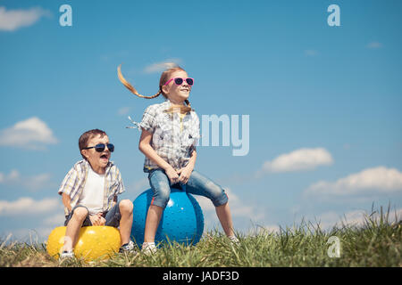 Frère et sœur jouant sur le terrain à la journée. Les enfants s'amuser en plein air. Ils sauter sur des ballons gonflables sur la pelouse. Concept d'ami Banque D'Images