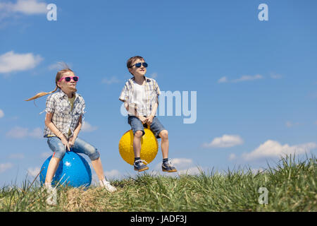 Frère et sœur jouant sur le terrain à la journée. Les enfants s'amuser en plein air. Ils sauter sur des ballons gonflables sur la pelouse. Concept d'ami Banque D'Images