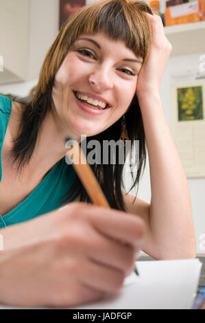 Kopf-und-Schulter-Ansicht eines jungen Frau am Tisch, brünetten Schreibstift sitzend mit der und Schnellhefter en main vor sich liegend Banque D'Images