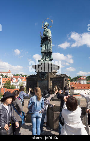 Les touristes se frottant les reliefs en laiton à la base de la statue de saint Jean Népomucène pour la chance. Le Pont Charles, Prague, République Tchèque Banque D'Images